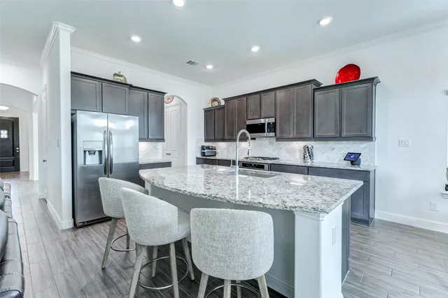 a kitchen with granite countertop a sink and a stove top oven with wooden floor