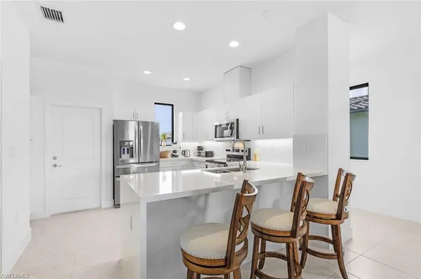 a kitchen with a dining table chairs and refrigerator