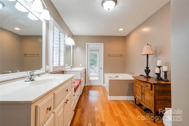a spacious bathroom with a double vanity sink a mirror and a bathtub