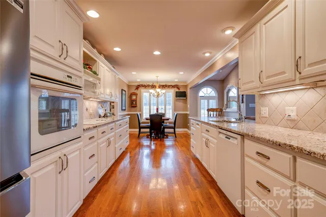 a large kitchen with stainless steel appliances granite countertop a lot of counter space and wooden floors