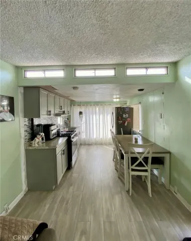 a kitchen with stainless steel appliances kitchen island granite countertop a table chairs in it and a wooden floors