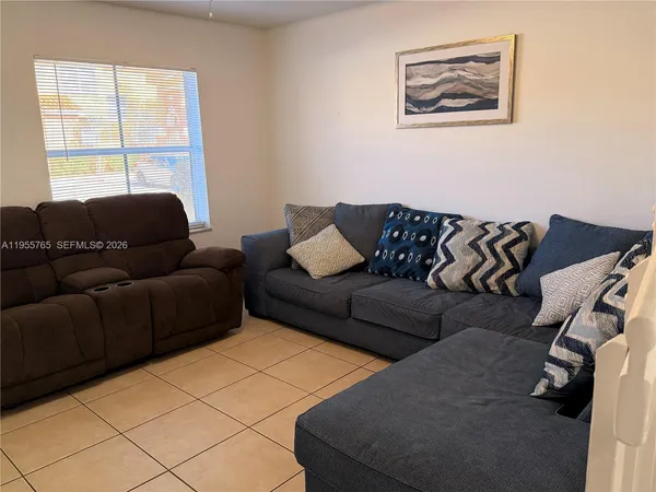 a living room with stainless steel appliances furniture and a large window
