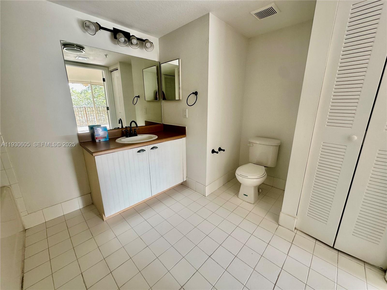 4190 San Marino Boulevard, Unit 303 West Palm Beach, FL 33409 - Photo 12 of 19 a bathroom with a sink a toilet and a mirror