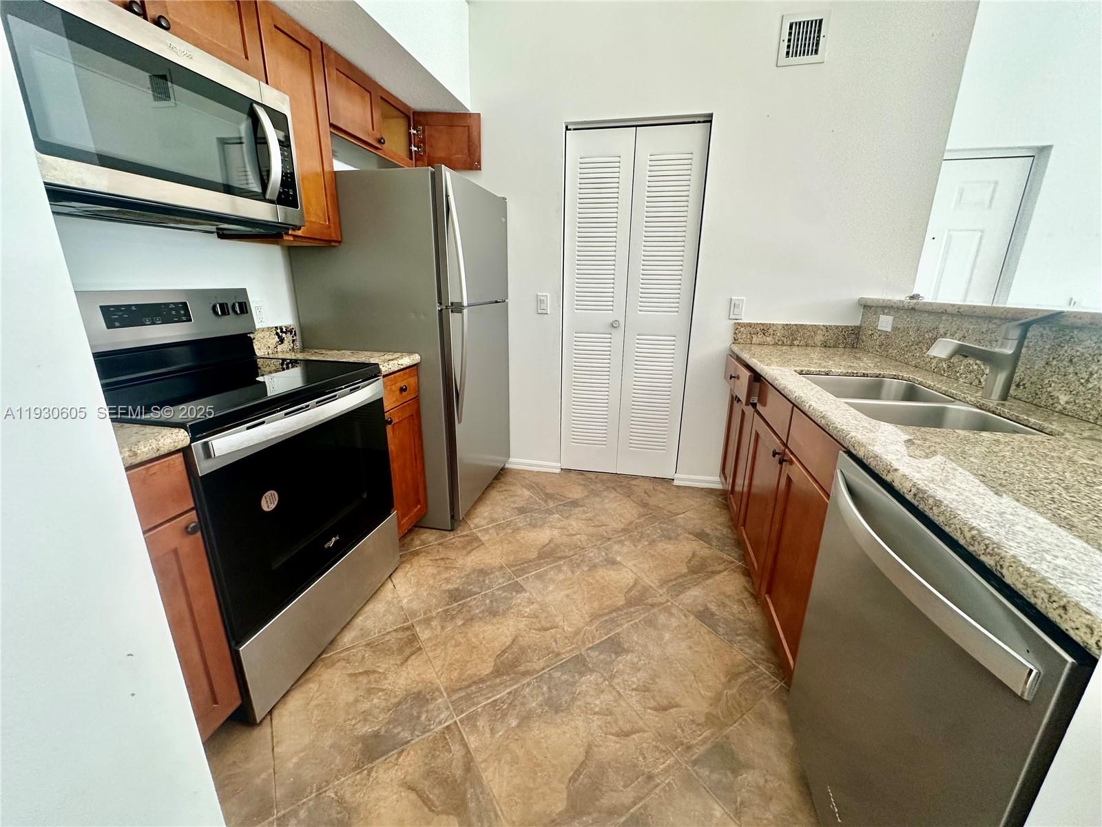 4190 San Marino Boulevard, Unit 303 West Palm Beach, FL 33409 - Photo 7 of 19 a kitchen with stainless steel appliances granite countertop a stove a sink and a refrigerator