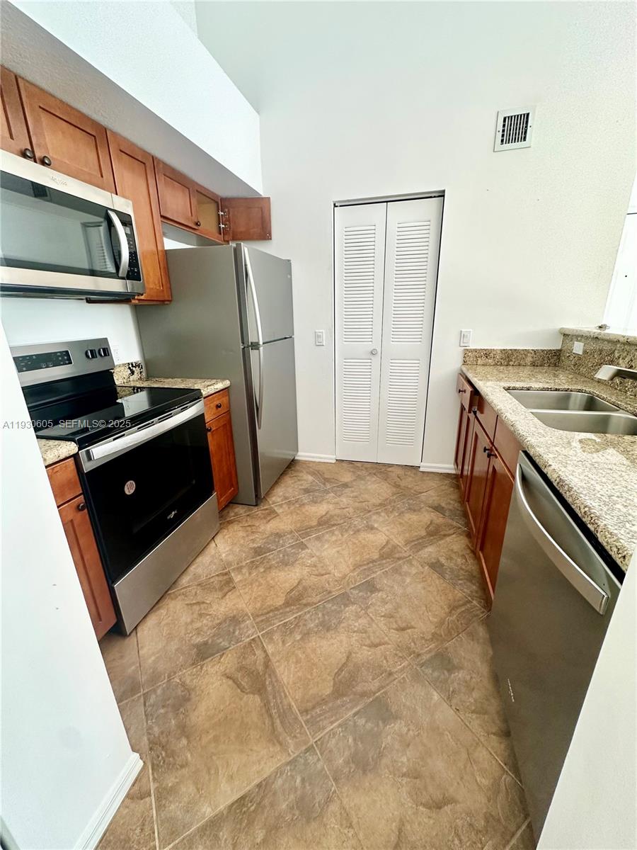 4190 San Marino Boulevard, Unit 303 West Palm Beach, FL 33409 - Photo 8 of 19 a kitchen with stainless steel appliances granite countertop a stove a refrigerator and a sink