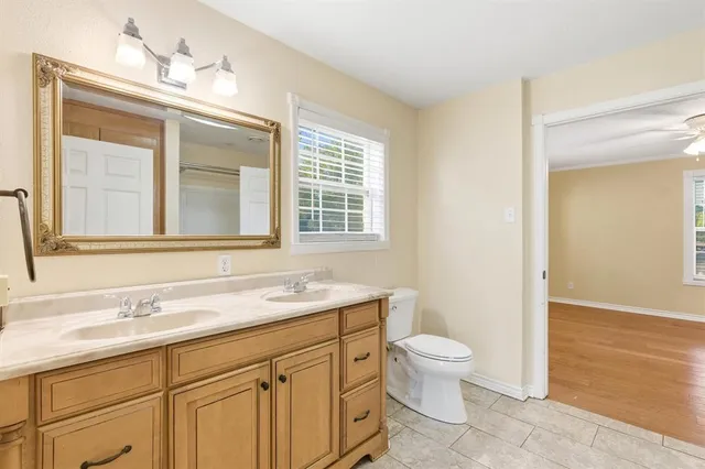 a bathroom with a granite countertop sink a toilet and a mirror