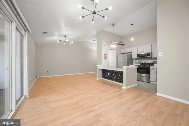 a large white kitchen with kitchen island a stove a sink a refrigerator and chandelier