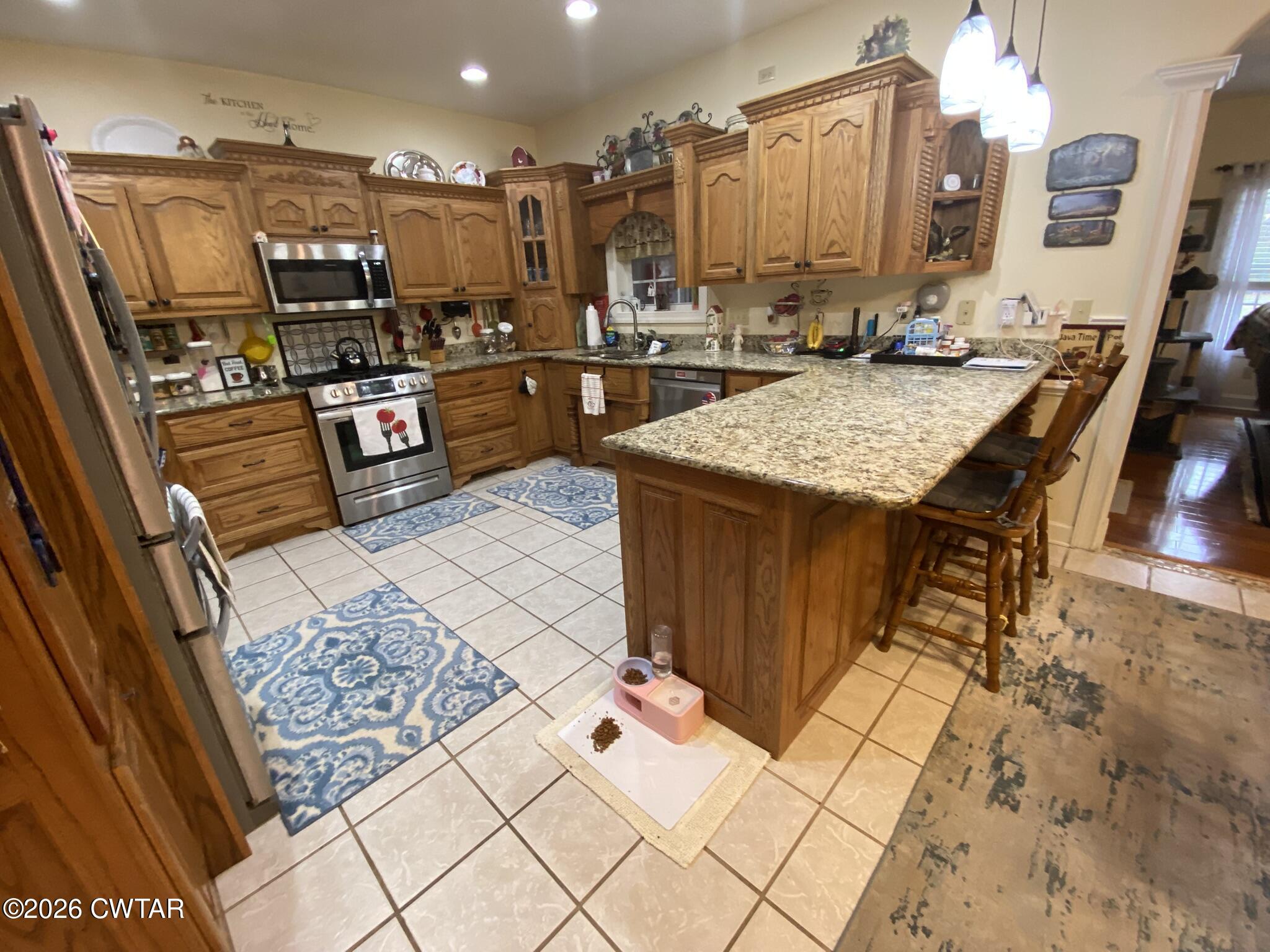 495 Knuckles Road Henderson, TN 38340 - Photo 17 of 80 a kitchen with stainless steel appliances kitchen island granite countertop a table chairs in it and wooden floor