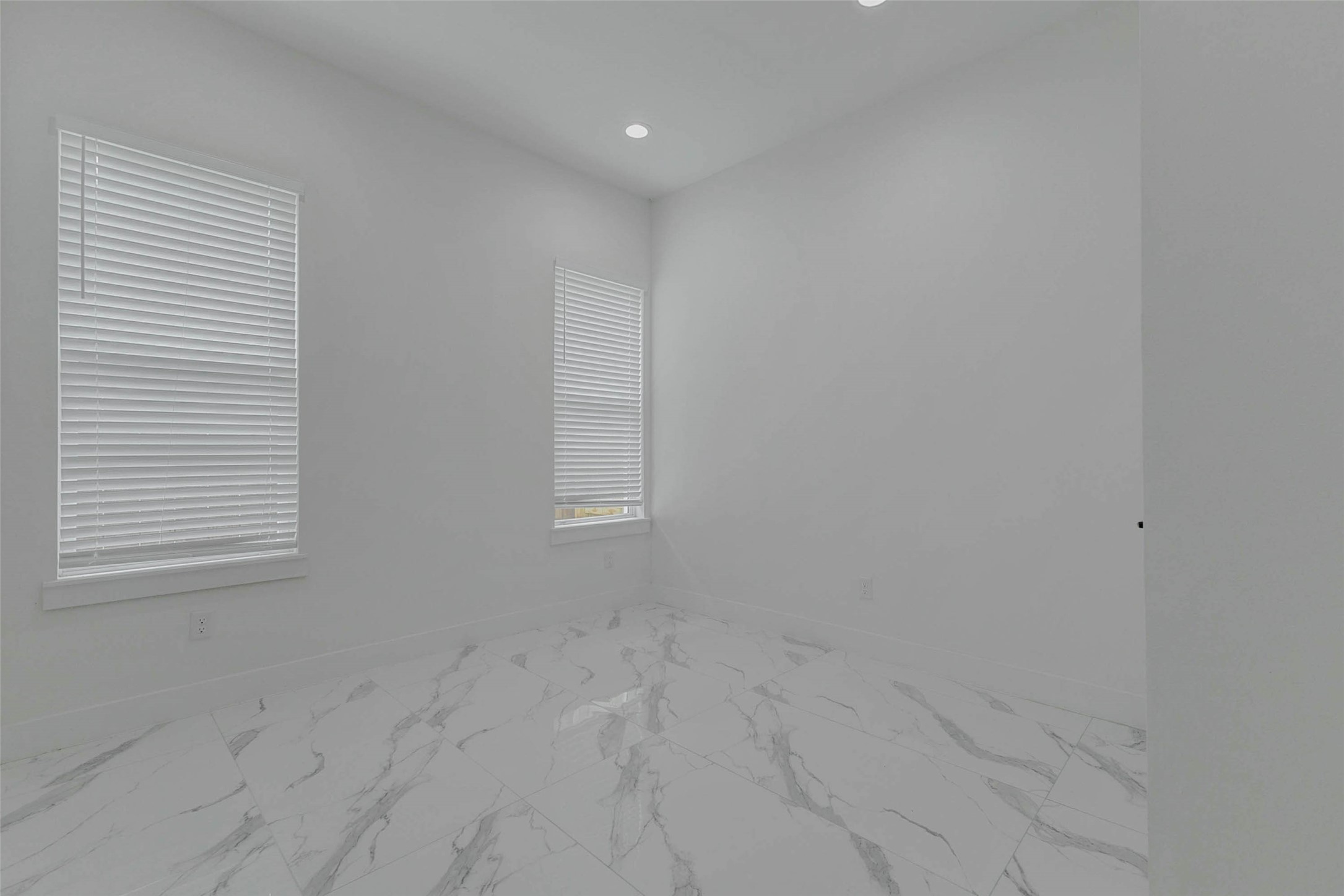 5705 Elysium Street Houston, TX 77091 - Photo 9 of 22 Secondary bedroom with glossy marble-look flooring, recessed lighting, tall ceilings, and a large window with blinds. The crisp white walls and bright neutral finishes create a fresh, flexible room ideal for guests, a home office, nursery, fitness space, or additional private retreat.