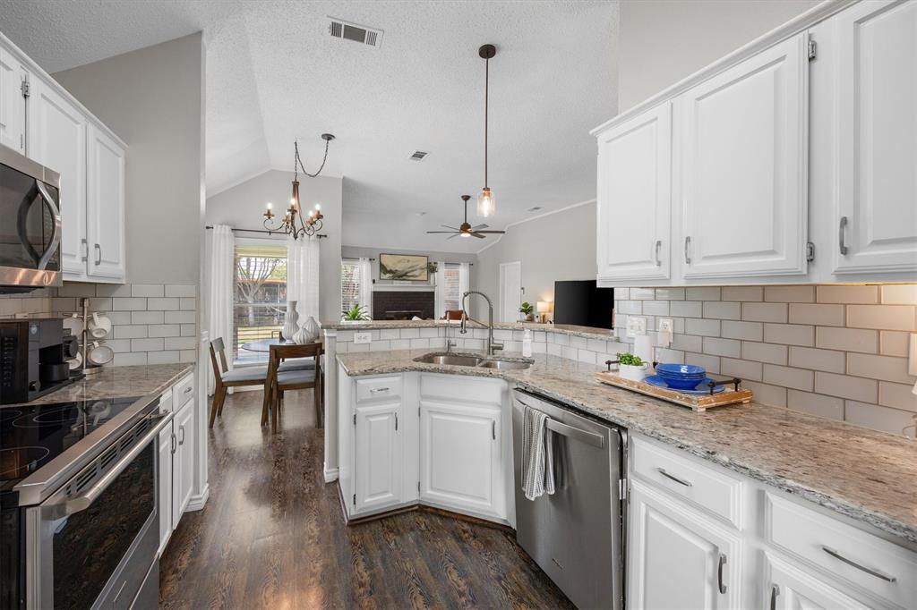 10714 Huntington Road Frisco, TX 75035 - Photo 6 of 24 Kitchen featuring white shaker-style cabinetry, gooseneck faucet, pendant lighting, granite countertops, white subway tile backsplash, stainless steel appliances, and wood-finish flooring