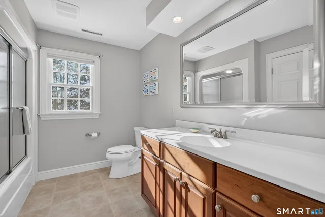 a bathroom with a sink toilet and two mirror