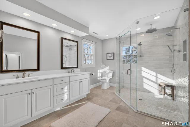a spacious bathroom with double vanity a mirror and shower