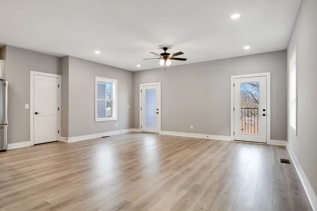 a view of an empty room with window and wooden floor