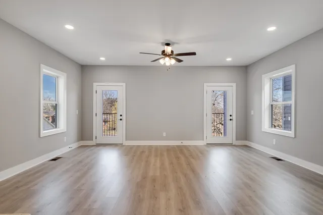 a view of an empty room with a window and wooden floor