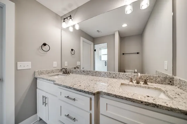 a bathroom with a granite countertop sink double and mirror