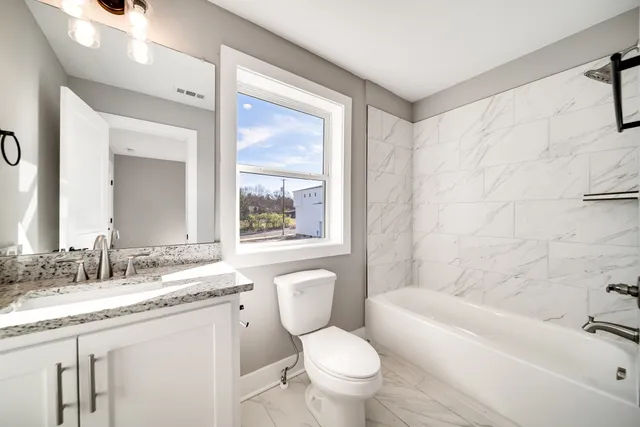 a bathroom with a granite countertop toilet a sink and a bathtub