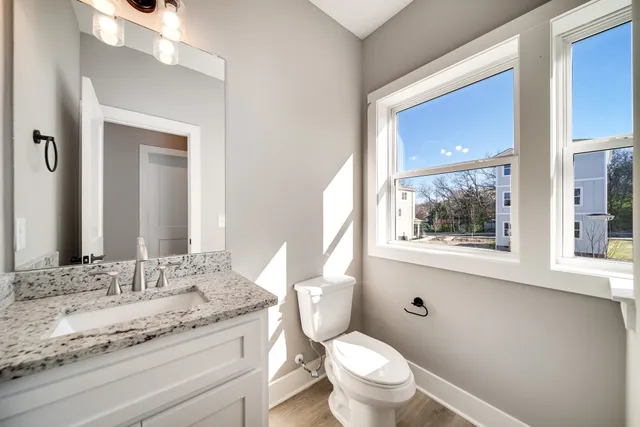 a bathroom with a granite countertop toilet sink and mirror