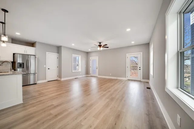 a view of an empty room with window and wooden floor