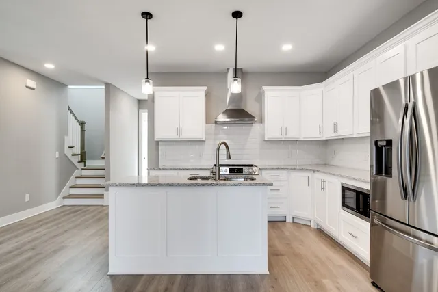 a large kitchen with stainless steel appliances granite countertop a sink a stove and a refrigerator