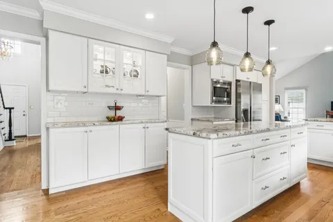 a kitchen with a white cabinets and chandelier stainless steel appliances