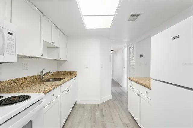 a kitchen with granite countertop a sink and a stove top oven