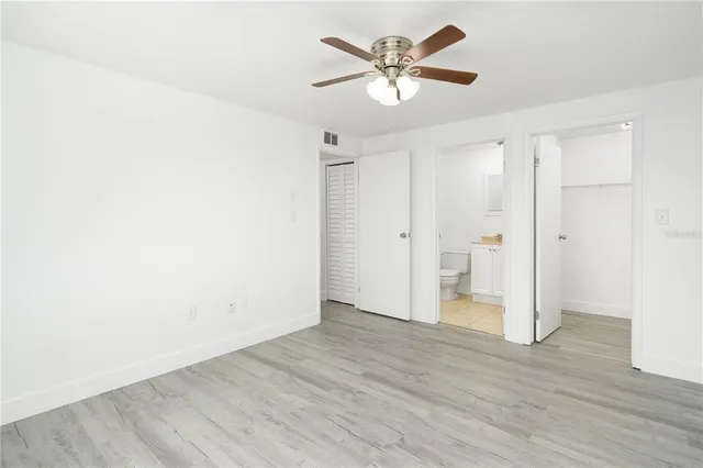an empty room with wooden floor and ceiling fan