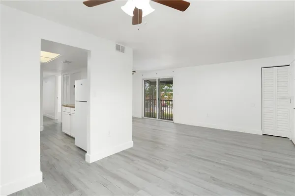 an empty room with wooden floor chandelier and windows