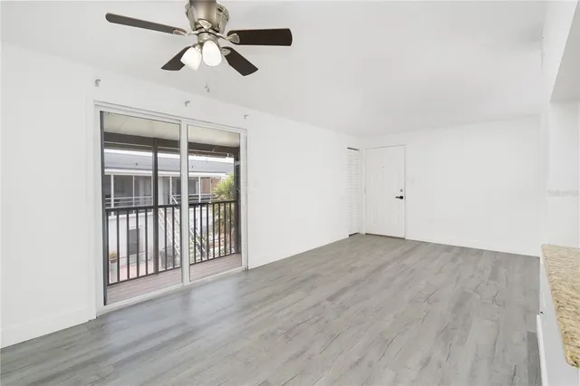 an empty room with wooden floor fan and windows