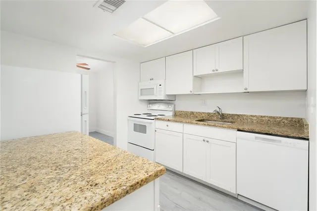 a kitchen with granite countertop white cabinets and white appliances