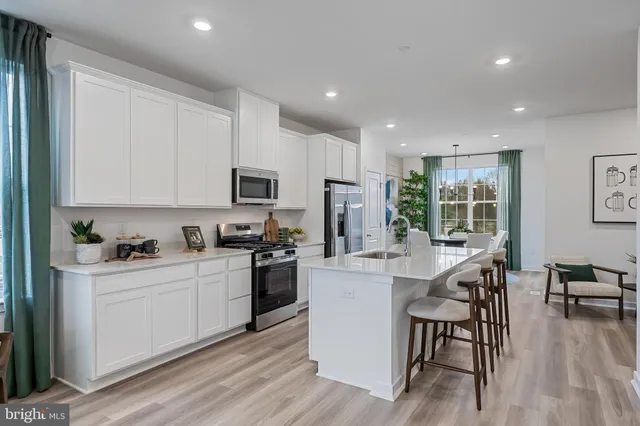 a kitchen with a sink a stove a refrigerator cabinets and dining table