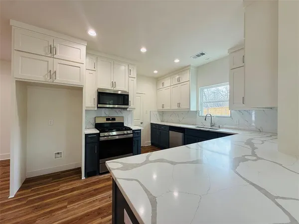 a large kitchen with stainless steel appliances kitchen island granite countertop a stove a sink and a microwave