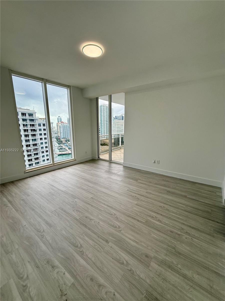 901 Brickell Key Boulevard, Unit 3102 Miami, FL 33131 - Photo 12 of 15 an empty room with wooden floor and windows