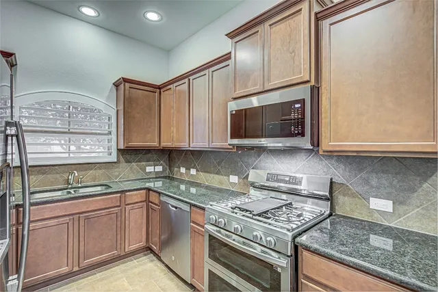 a kitchen with stainless steel appliances granite countertop a sink stove and cabinets