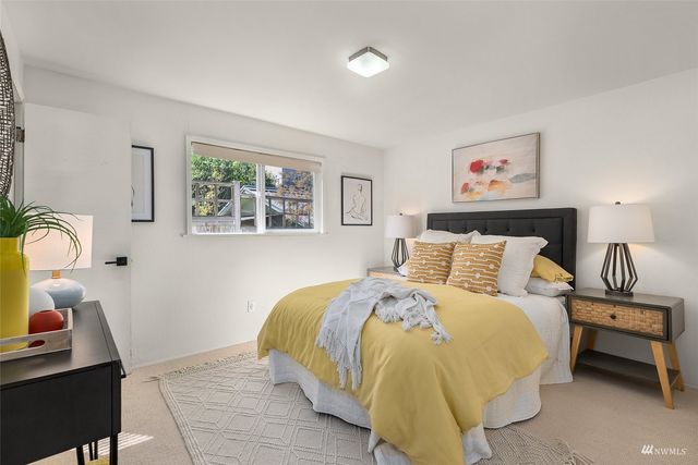 a bedroom with a bed a dresser next to a window