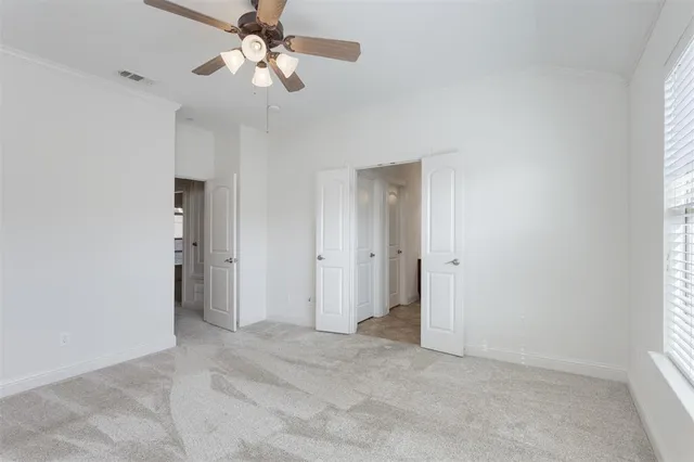 a view of an empty room and chandelier fan
