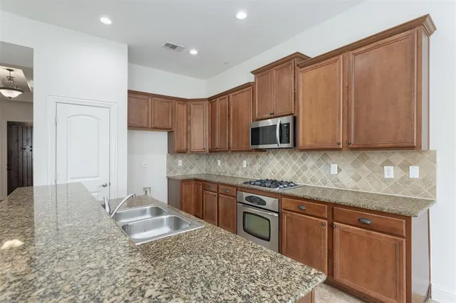 a kitchen with stainless steel appliances granite countertop a sink stove and microwave