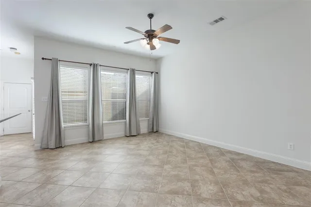 an empty room with chandelier fan and windows