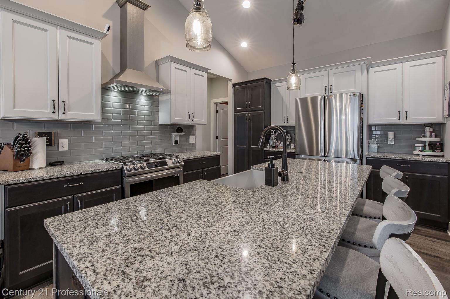 4914 TORATOLA Lane Howell, MI 48843 - Photo 16 of 39 Kitchen with decorative backsplash, stainless steel appliances, light stone countertops, vaulted ceiling, and two tone color scheme