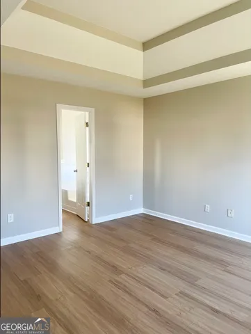 a view of an empty room with wooden floor and closet