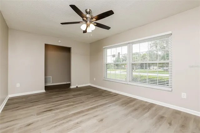 a view of an empty room with a window and wooden floor