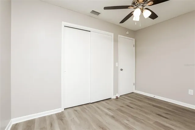 an empty room with wooden floor fan and windows