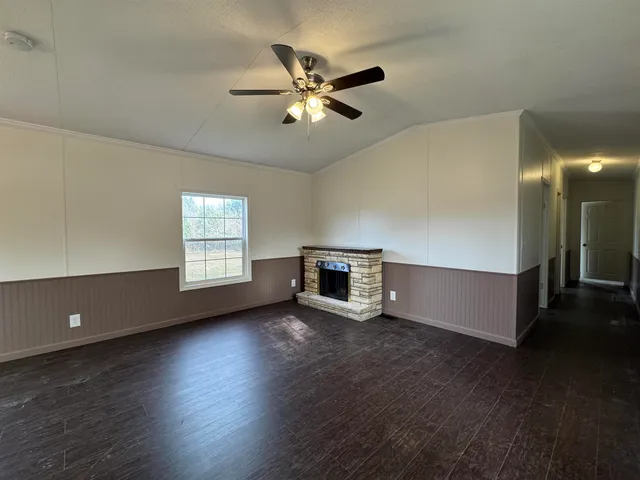 a view of an empty room with wooden floor and a ceiling fan