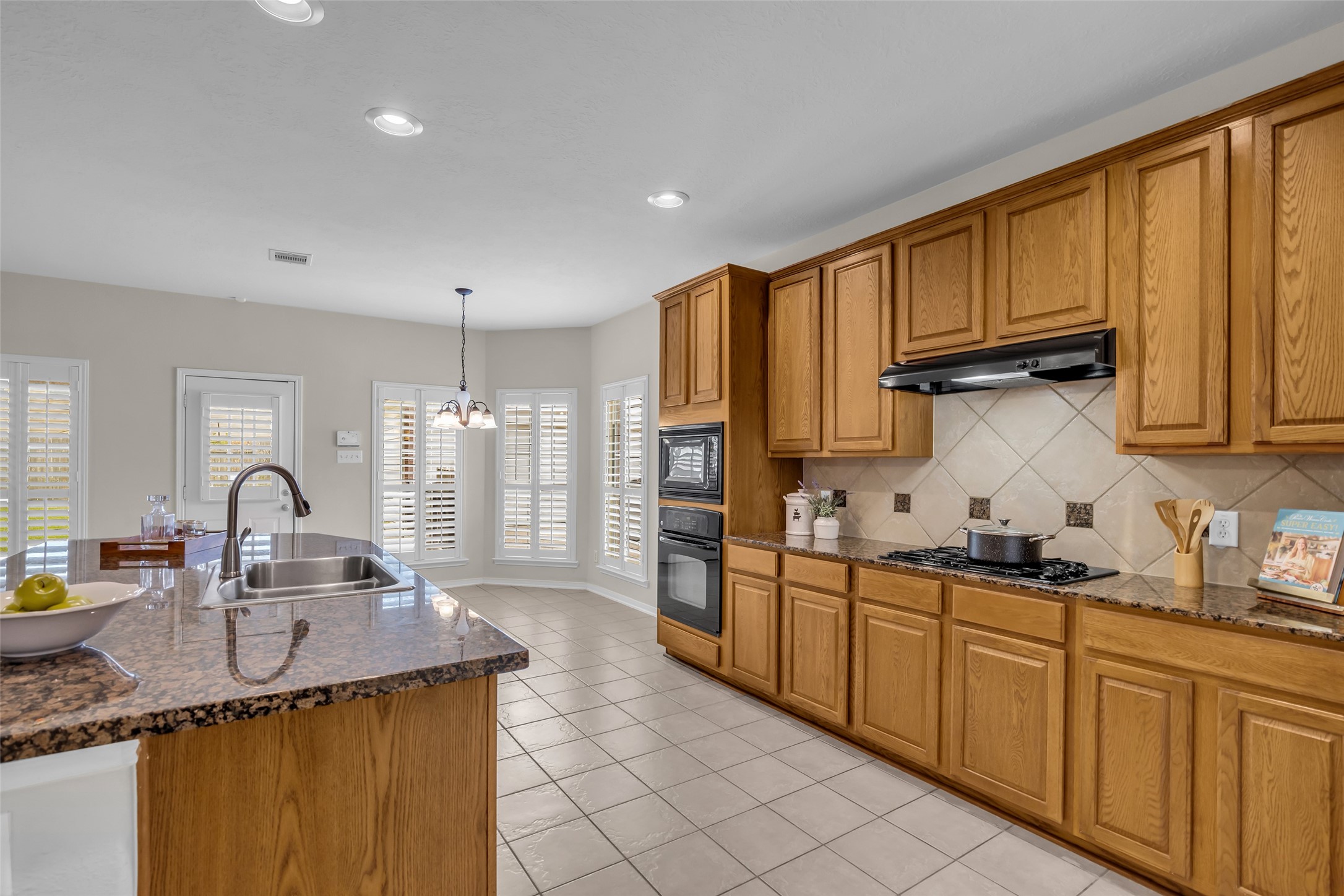6807 Chapelfield Lane Houston, TX 77049 - Photo 14 of 42 This spacious kitchen features warm wood cabinetry, granite countertops, and a modern gas cooktop. Natural light floods in through the large windows with plantation shutters, and a cozy breakfast nook is perfect for casual dining.