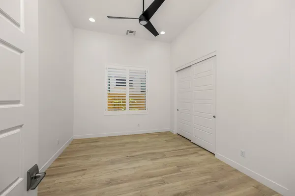 an empty room with wooden floor and windows