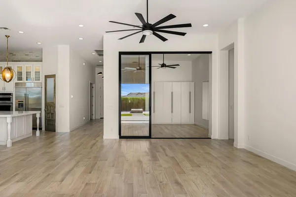 an empty room with wooden floor and a ceiling fan