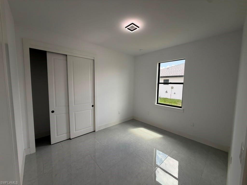 907 Homestead Road South Lehigh Acres, FL 33974 - Photo 40 of 43 Bright room featuring a single window, a flush-mount ceiling light fixture, and a closet with bi-fold doors, all set on light-toned tile flooring