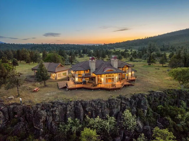 a view of a big house with a big yard and large trees