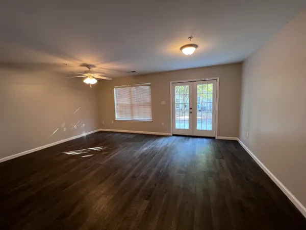 an empty room with wooden floor and windows