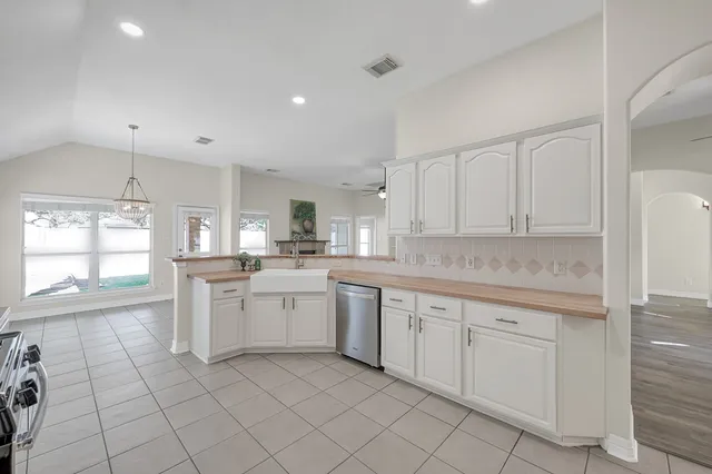 a kitchen with white cabinets appliances a sink and a window