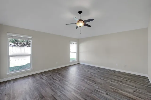 a view of empty room with wooden floor and fan